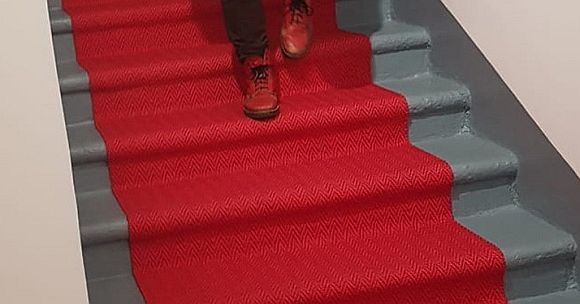 Roter Teppichläufer auf Treppenstufen mit roten Schuhen.